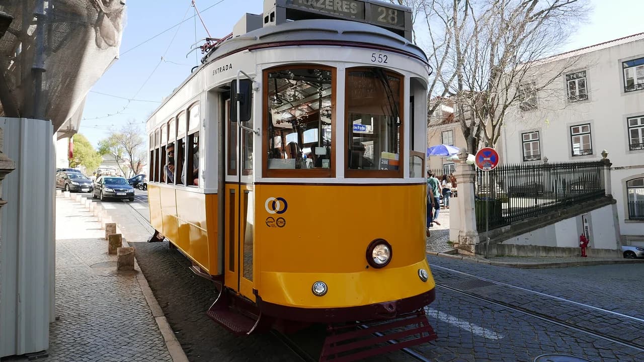 Yellow Tram 28 on a cobblestone street in Lisbon Alfama district
